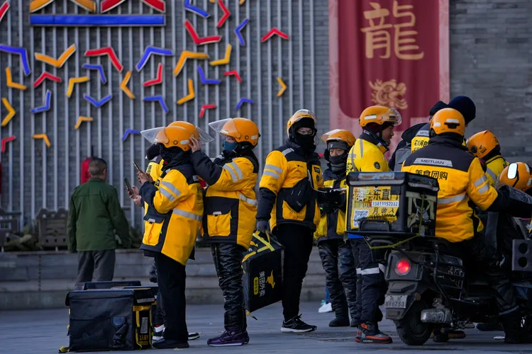 5日的北京街頭，一群美團外賣的外送員等待接單。美聯社