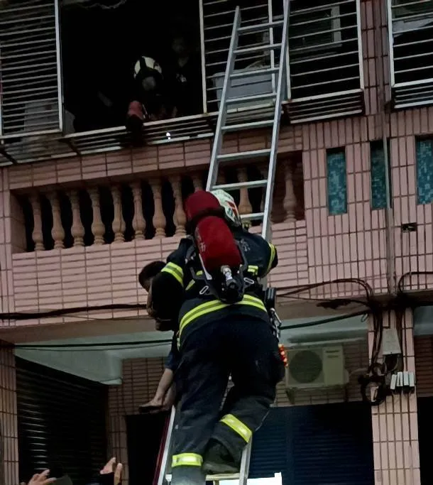 消防員架設梯子從2樓救出2名男童。翻攝畫面