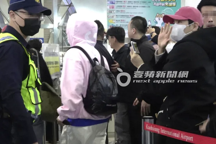 SJ厲旭（右）抓著手機支架邊錄影邊揮手記錄，粉紅色帽T的東海準備走進海關。特勤中心攝