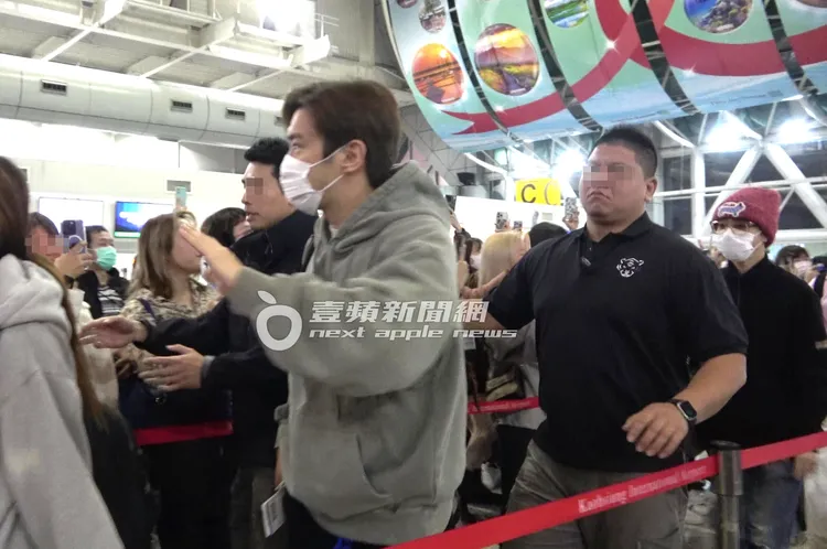 SJ始源（左）對左右兩邊粉絲揮手，戴紅色毛帽的藝聲緊跟在後。特勤中心攝