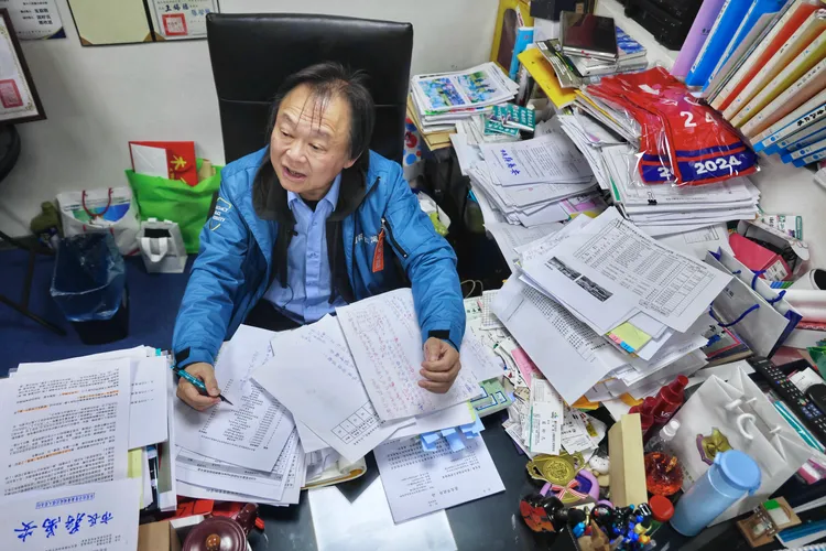 王世堅不用電腦，文件和預算書堆滿辦公桌。林林攝