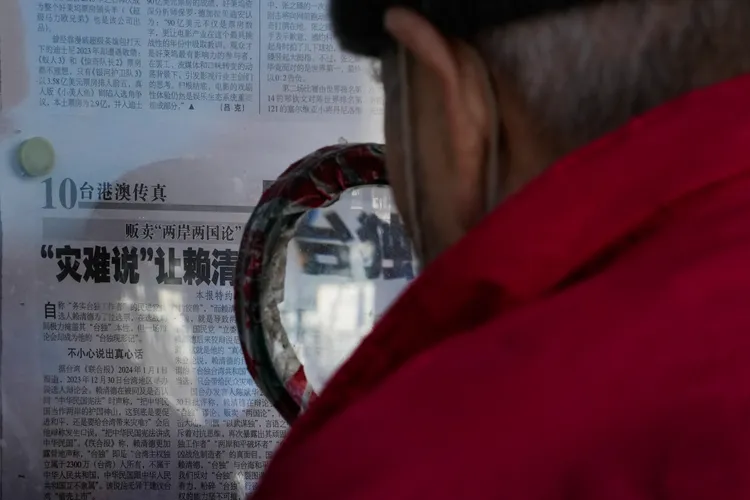 根據中國民政部，截至2022年底，中國65歲及以上老年人口2億978萬人；圖為3日北京一名長者拿放大鏡看報紙上的台灣新聞。美聯社