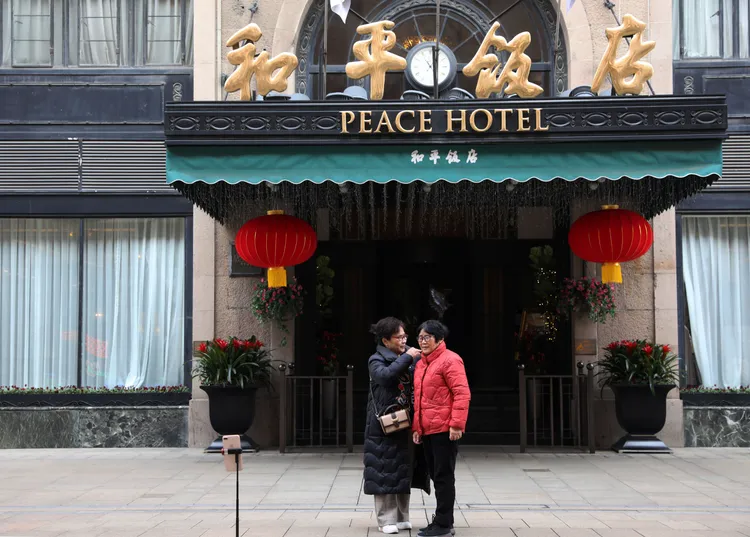 民眾在上海和平飯店前整理衣裝，準備拍照。新華社