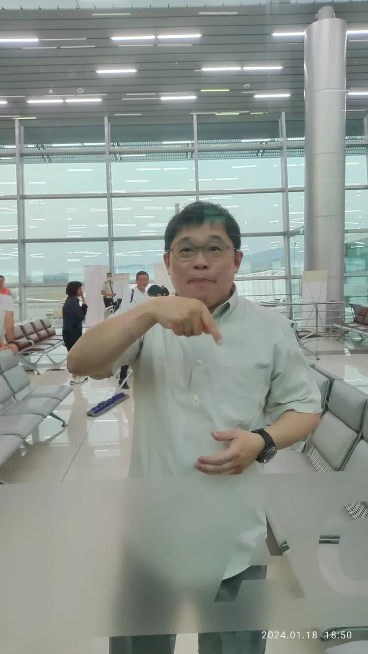 隔著落地窗K董跟旅客比手畫腳，畫面相當趣味。翻攝自臉書「星宇航空 討論區 STARLUX Airlines」