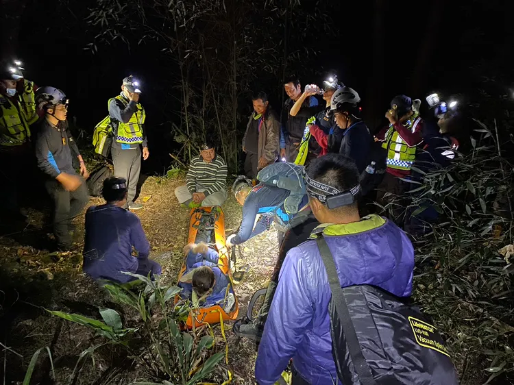 消防人員將上山打獵的男子搬上擔架，運回山下送醫。民眾提供