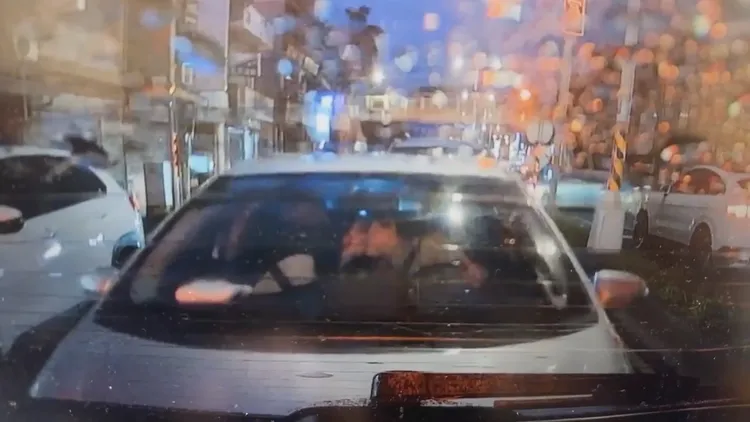 白車情侶忘我熱吻、唇齒交纏，完全沒注意到車輛緩緩向前滑行。翻攝自臉書「爆料公社」