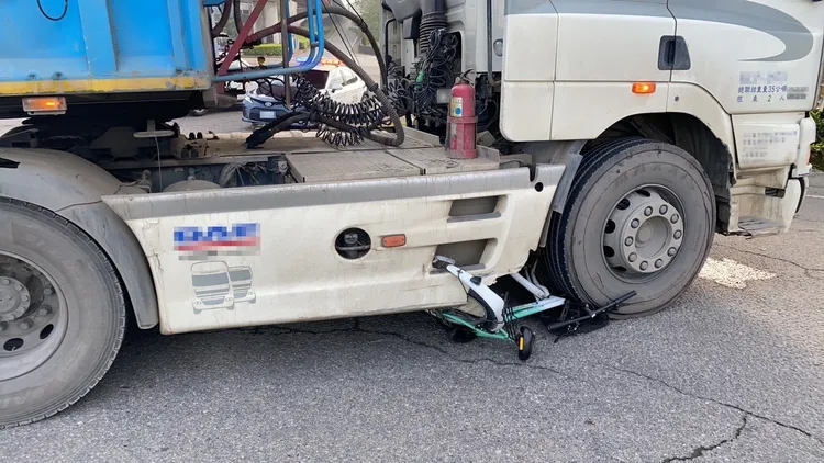 自行車卡在砂石車右前輪下。民眾提供