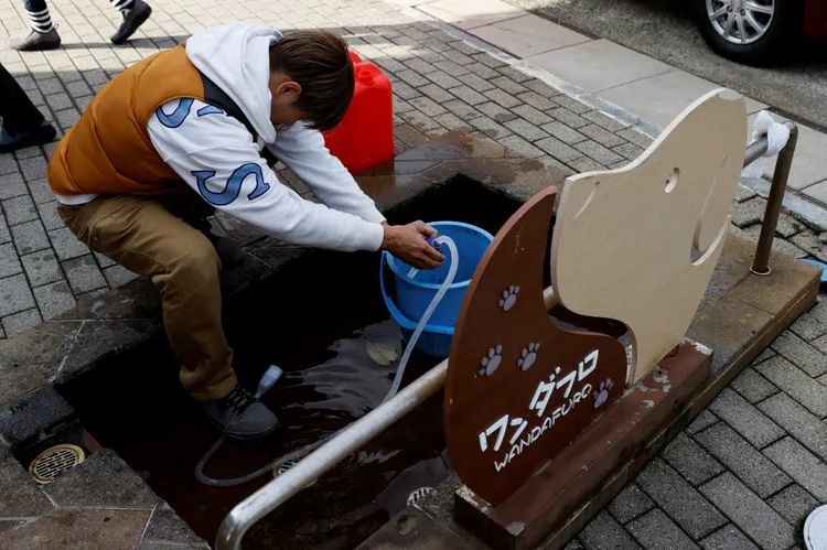 石川縣輪島市災民今天提著水桶到狗狗風呂接水。路透社