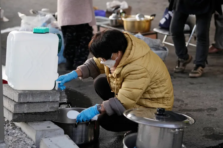 石川縣穴水町避難所的災民，今天在避難所外用公用水洗滌器皿。美聯社