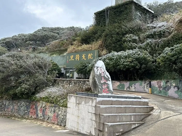 寒流發威，馬祖北竿壁山22日深夜起罕見下雪，北竿鄉長吳金平23日拍攝照片，屋簷、樹梢、地面與石碑都有積雪，與「枕戈待旦」標語相輝映。（吳金平提供）中央社