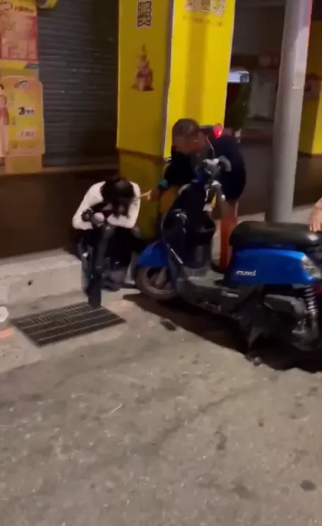 溫翠蘋遭洋男狠踹後，表情痛苦蹲坐在騎樓，一旁洋男則不斷要她冷靜。翻攝自記者爆料網