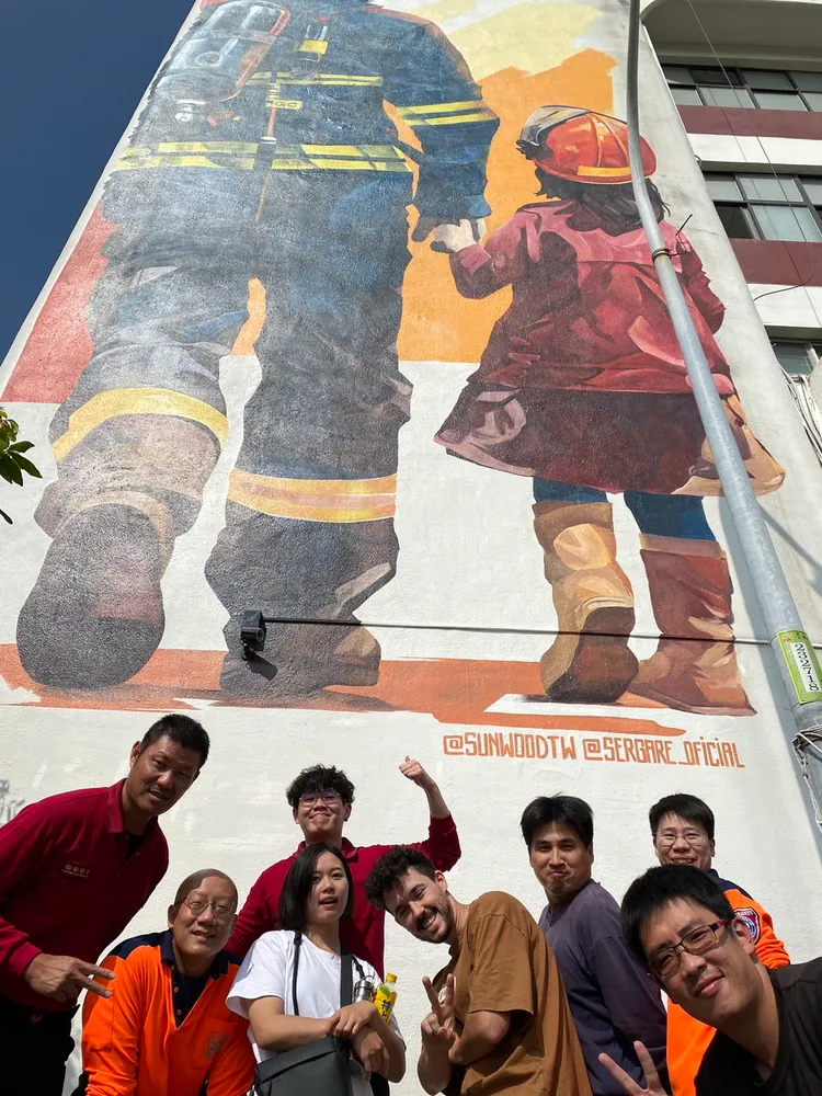 杉木藝術創辦人劉亭彣(白衣)邀請西班牙藝術家GARE(褐衣)一同繪製壁畫。消防局提供