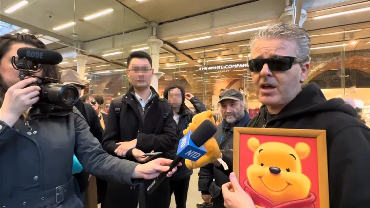 卡瓦納拿著維尼肖像與玩偶受訪，表達對於日前被小粉紅鬧場的看法。翻攝Youtube/Dr K Boogie Woogie (Brendan Kavanagh)