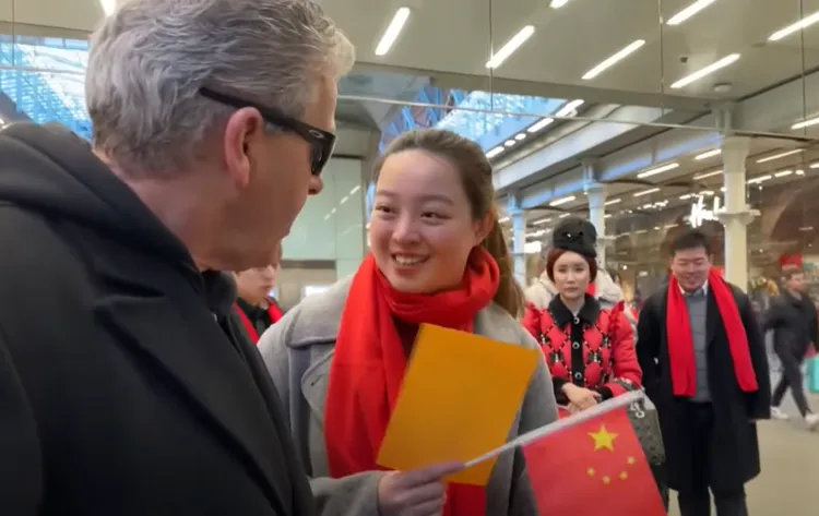 手持中國五星旗的年輕女性前來向鋼琴家卡瓦納交涉，她們的成員中「有人不想被拍到」。後方2人為同團成員。翻攝Youtube/Dr K Boogie Woogie  (Brendan Kavanagh)
