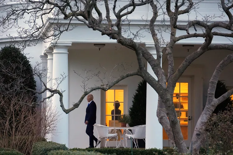 圖為拜登在白宮走廊行走。美聯社