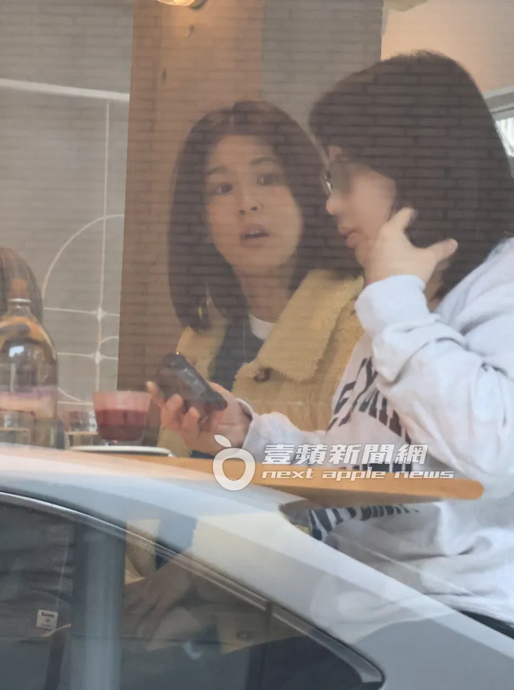 曾沛慈（左）在咖啡廳專注看著身旁友人聽她報告工作事項。特勤中心攝