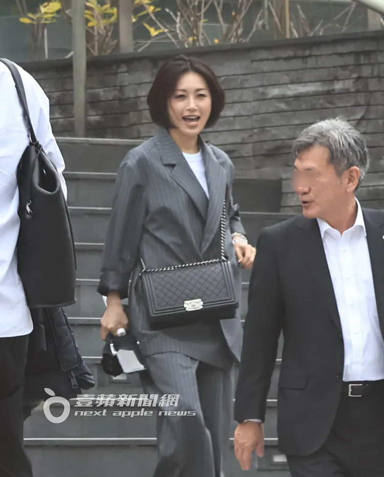 酒井法子（左）拿著手機與自拍架下樓，開心與同行友人聊天。特勤中心攝