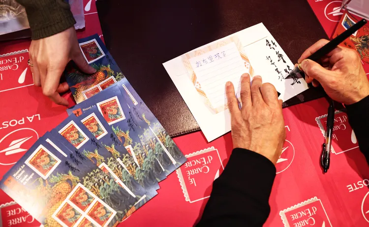 陳江洪為法國集郵迷寫下中文名字和新年快樂。新華社
