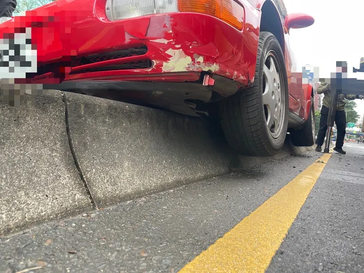 保時捷911跑車「騎上」分隔島，底盤零件恐嚴重受損。翻攝自記者爆料網
