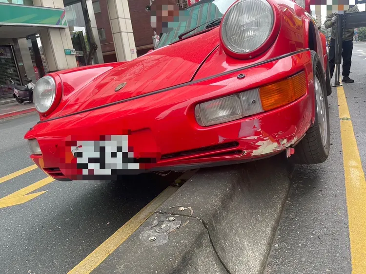保時捷911跑車「騎上」分隔島，底盤零件恐嚴重受損。翻攝自記者爆料網
