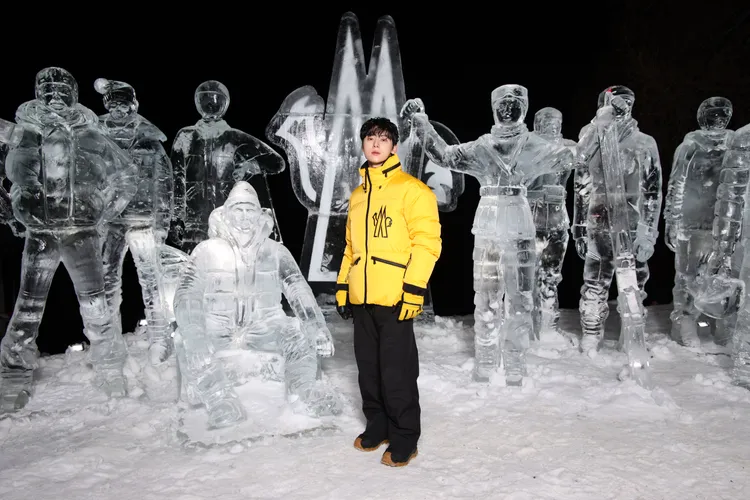 黃旼炫在雪地中身穿黃色羽絨衣搭配黑色滑雪褲。品牌提供