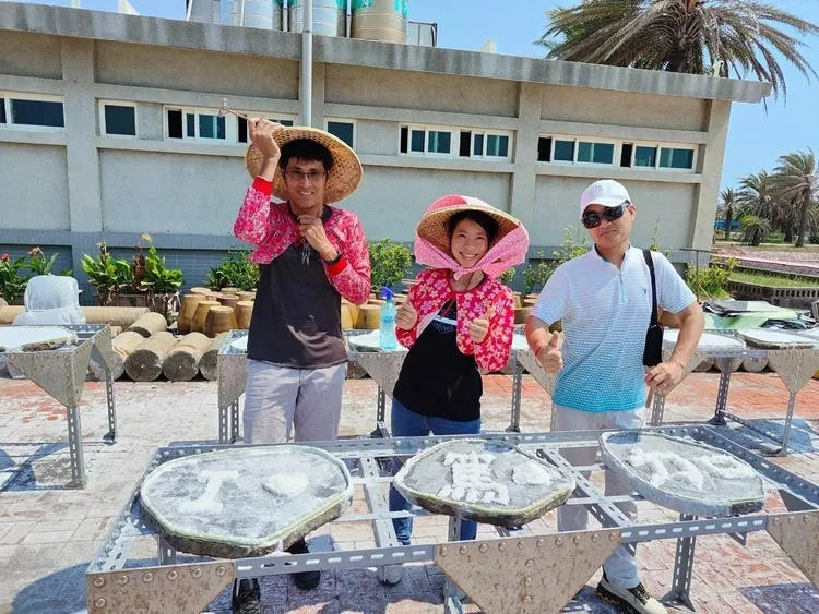 七股鹽山首創「石板天日曬鹽」，遊客穿斗笠、袖套曬鹽，一秒回到過往鹽工時代。業者提供