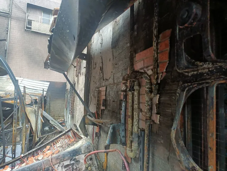 新北市八里區一處貨櫃倉庫今天清晨4時許發生火警，所幸無人傷亡，不過稍微延燒至鄰宅陽台處。新北市消防局提供