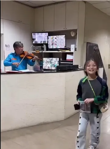 保全在小女童面前表演小提琴，當場演奏出日本卡通「龍貓」主題曲「豆豆龍」，讓女童驚呼連連！翻攝《爆廢1公社》社團