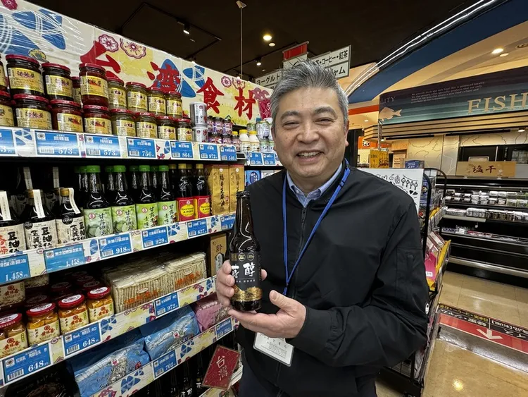 日本熊本縣唯一百貨公司鶴屋的海外進出口事業的子公司甘夏Royal社長岩下晉也23日在超市「鶴屋FOODY ONE楠店」台灣食材區推薦一款酒品。他說，超市正摸索台積電員工的親屬回台灣會買什拌手禮。中央社