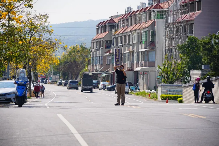 為了拍攝黃花風鈴木美景，男子拿「大砲」硬是站在路中央拍照以身犯險，對旁人警告充耳不聞。臉書「爆料公社二社」