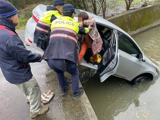 天雨路滑老婦開車倒栽蔥　連人帶車墜排水溝！警及時救援脫困