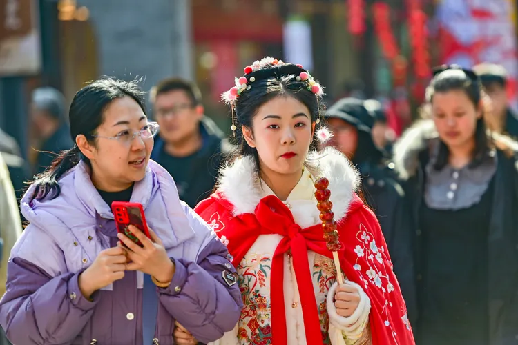 穿著漢服的女性12日在山東省青州古城景區遊覽，手裡還拿著糖葫蘆。新華社