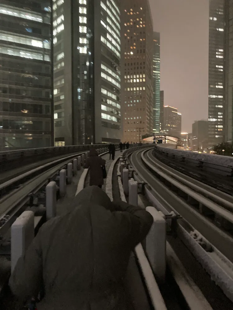 2輛百合海鷗號列車今晚因大雪受困汐留站前後，乘客被迫下車走積雪軌道回到汐留站離開。翻攝X