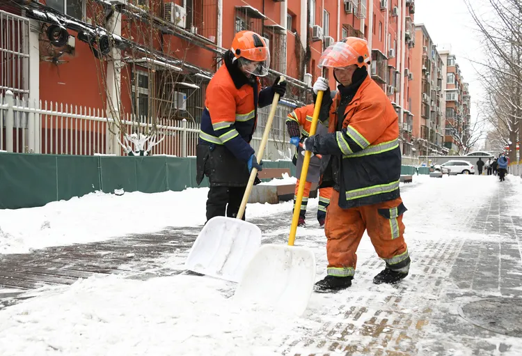 北京的工作人員在海淀區北太平莊街道文慧園路除雪。新華社