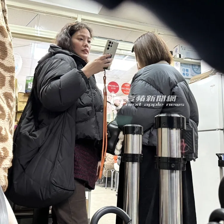 李維維（右）與翊萱排隊吃米其林牛肉麵，滑手機把握時間。特勤中心攝