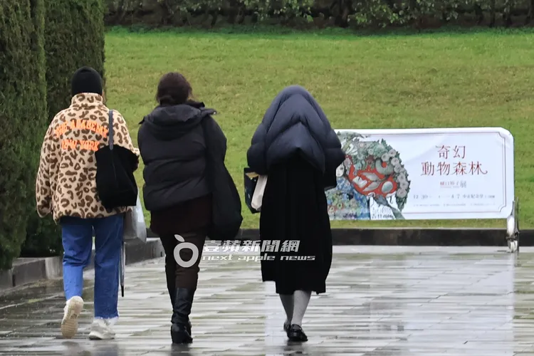 李維維（右起）將外套蓋在頭上，和翊萱漫步中正紀念堂廣場。特勤中心攝