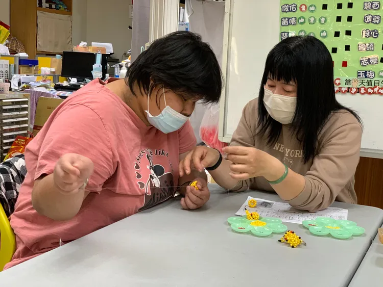 壹蘋_蔡惠名(右)教導慢飛天使製作串珠產品，覺得很有意義。王志弘攝