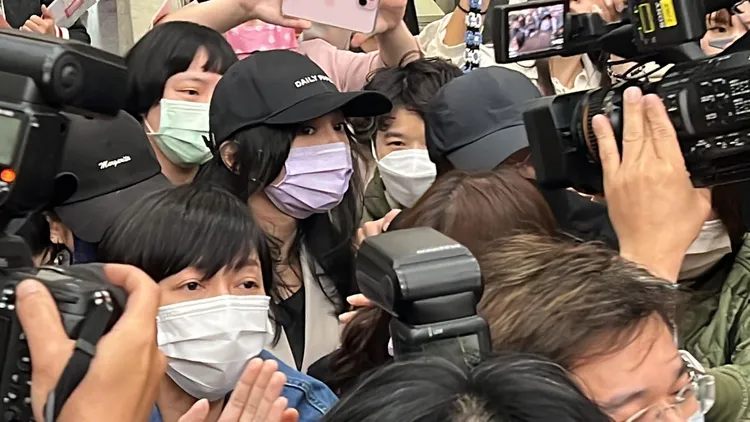 庭後Faye（黑帽、紫色口罩）在10多名親友護駕走出法院。陳彩玲攝