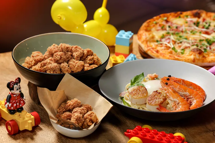 義饗食堂推出的「兒童節快樂分享餐」，餐點內容包括「香煎鮮蝦干貝溫泉蛋義麵」、「夏威夷披薩」、以及酥嫩多汁的「現炸雞米花」。業者提供