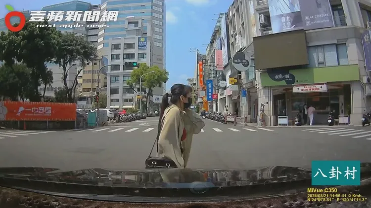 馬尾妹悠哉地邊講電話、邊從汽車前方散步通過。翻攝自臉書「八卦村 - 行車紀錄器影片上傳中心」