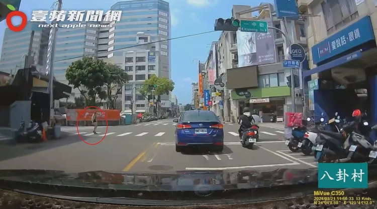 汽車順向明明是綠燈，駕駛人遠遠注意到一名熱褲馬尾妹(紅圈處)卻是無視車流，硬要闖紅燈通行。翻攝自臉書「八卦村 - 行車紀錄器影片上傳中心」