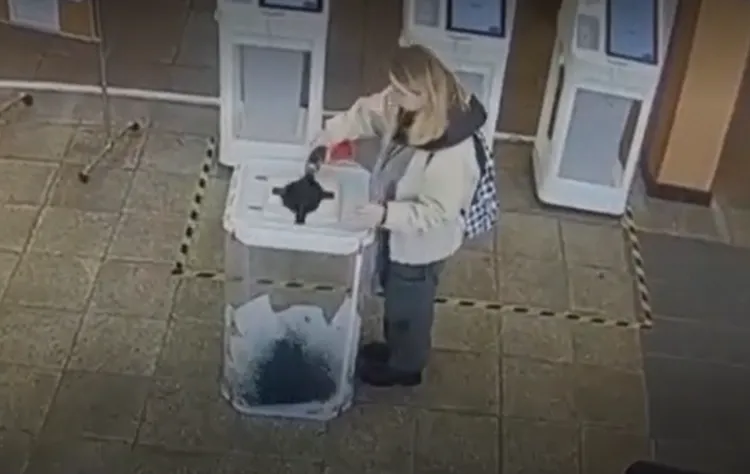 女子投入選票後，往內倒入染料。NBC