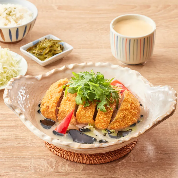 「品田牧場」新推出「黑醬蒜香豬排鍋膳」，用豚骨為湯底，蒜泥佐味，並淋上黑金竹炭醬和胡麻油提香，炸豬排浸於醬湯中，一口咬下享受雙重美味。業者提供