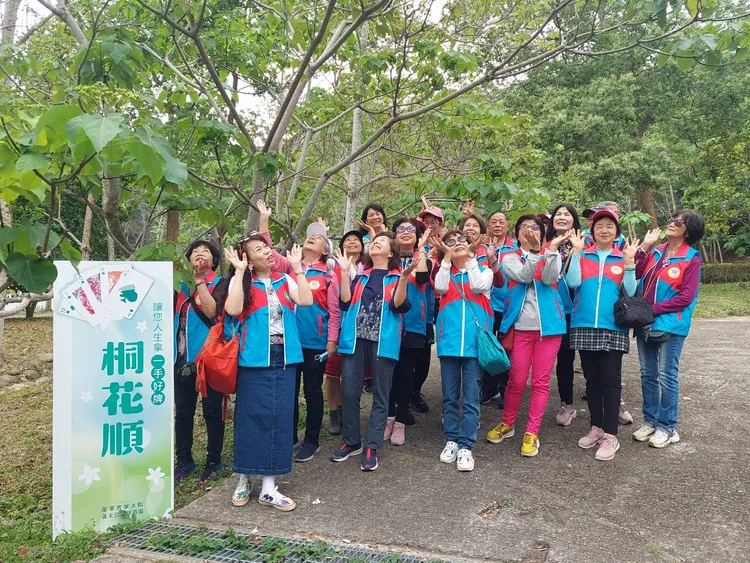 遊客於〈桐花順〉合影，盼沾沾好運氣。