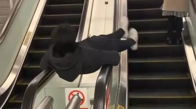 男子平躺電扶梯扶手上整個人不斷旋轉。翻攝自記者爆料網