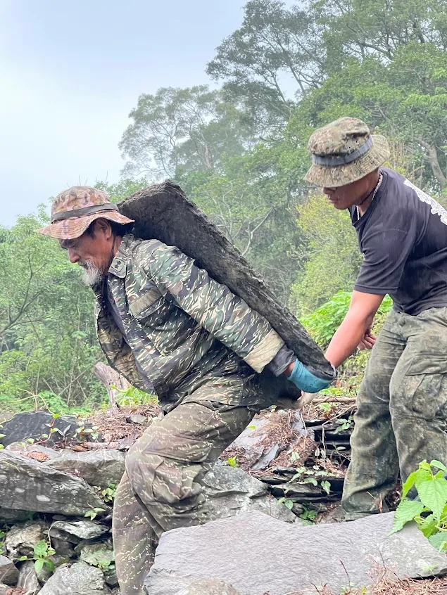 石板須以人力背負，得耗時半天。左為指導匠師小獵人Shikieyan(杜義雄)。台邦‧撒沙勒提供