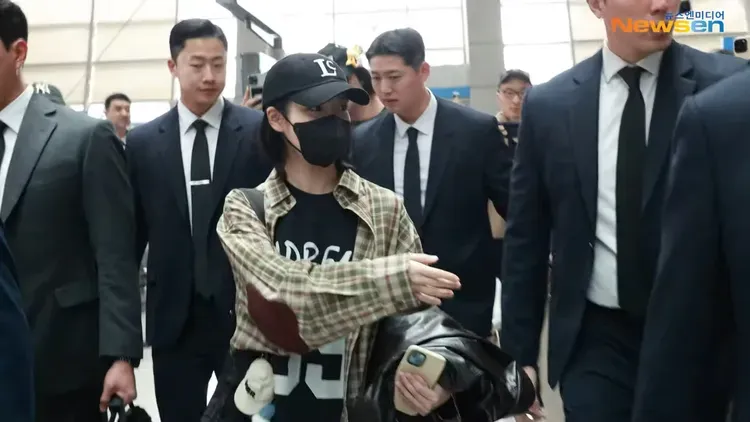 超級寵粉的IU在韓國機場伸出手示意要粉絲注意後方。翻攝Newsen YouTube