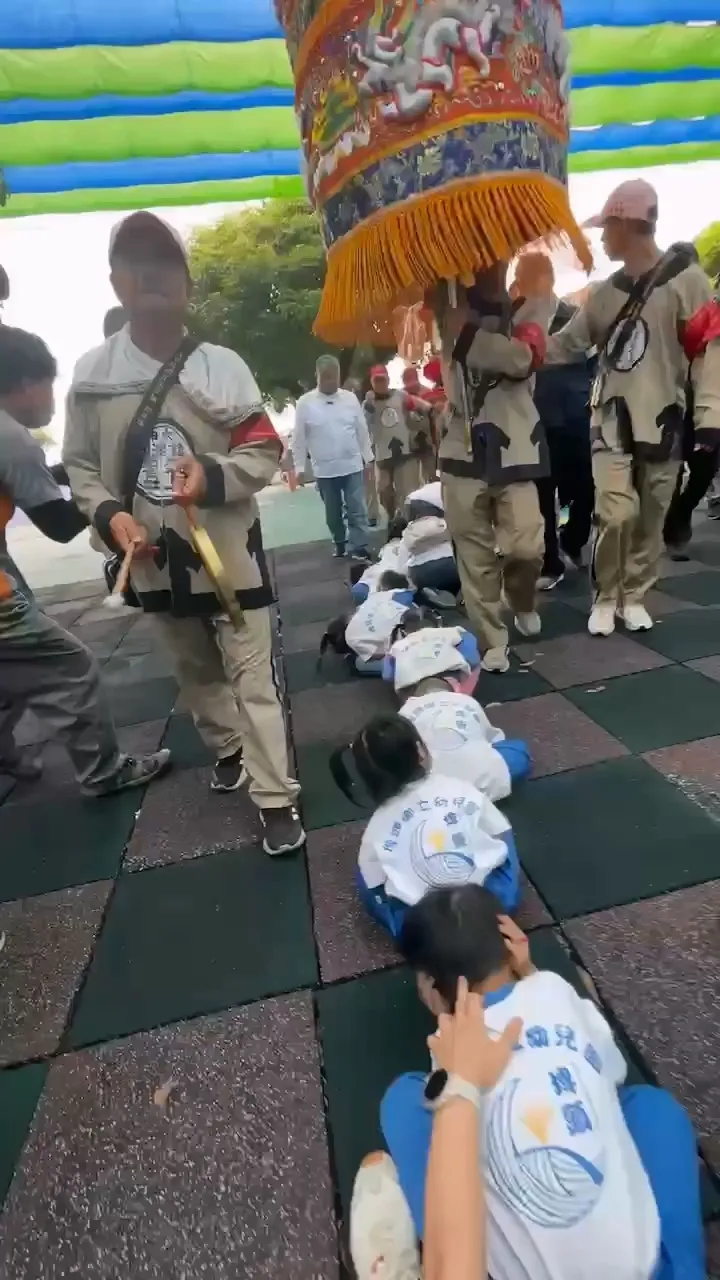 埤頭鄉立幼兒園學童鑽轎底，鎮瀾宮董事長顏清標全程觀看。大甲媽祖教師研習團提供