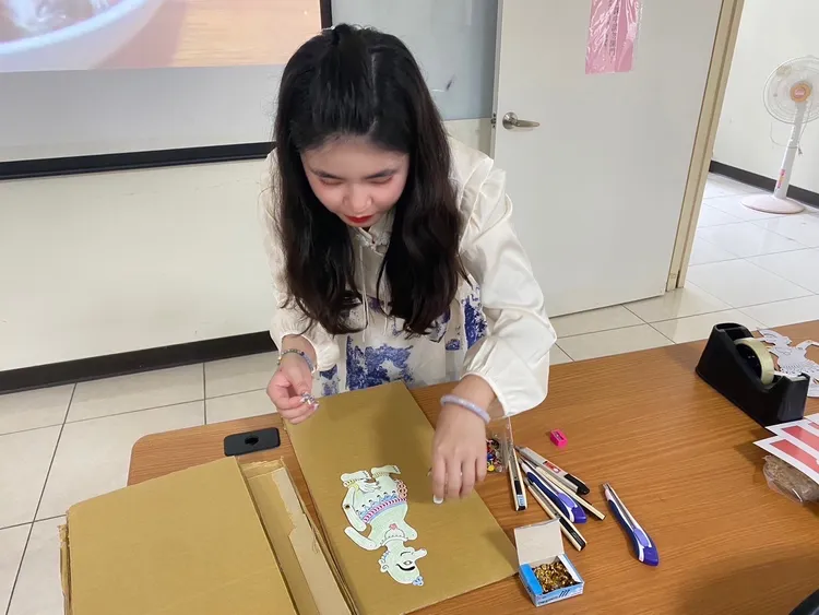 蔡佳伸以雙腳釘連接皮影人偶的關節，以便後續操作皮影人偶。翻攝畫面