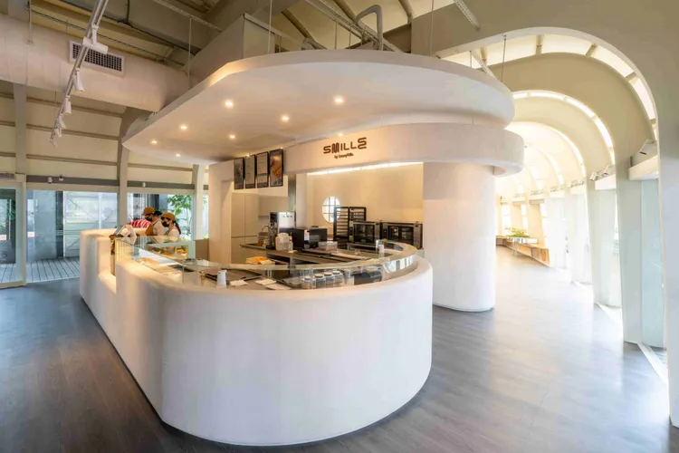 Smille駁二特區旗艦店，以代表品牌Logo的「S型吧檯」為主體，清新柔和的白泥牆營造空間的流暢感。業者提供